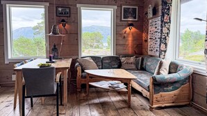 L’intérieur chaleureux d’un chalet avec une table à manger en bois, un canapé et une grande fenêtre donnant sur une vue imprenable sur les montagnes.
