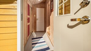 A wooden hallway with a striped rug leading to a white door with a window. - Synnøve by Interhome (Hellevik I Fjaler)