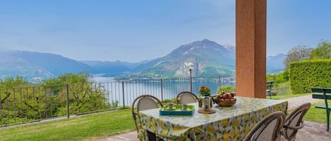 A terrace with a table set for two, overlooking a lake and mountains.