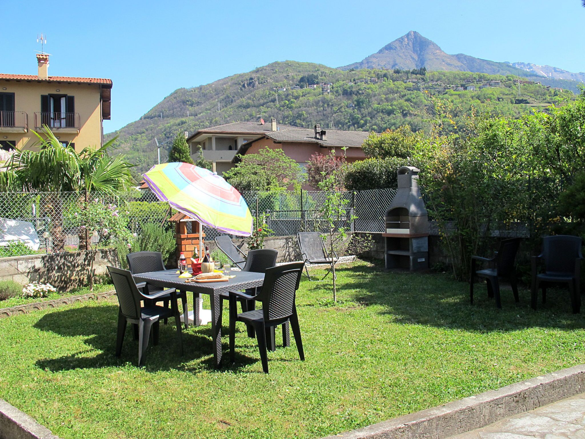 A patio with a table and chairs, a barbecue grill, and a mountain in the background.