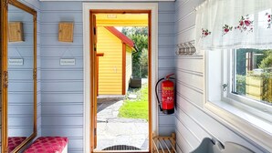 A narrow hallway with a wooden bench, a door leading outside, and a fire extinguisher mounted on the wall. - Gulehuset by Interhome (Reksteren)