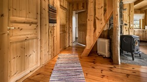 A wooden interior with a central staircase, a radiator, and a stove.