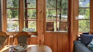 A wooden cabin with a dining table, chairs, and a sofa.