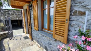 A stone building with wooden shutters and a stone wall.