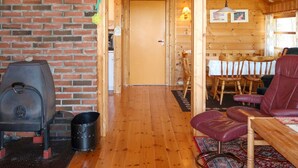 A wooden interior with a brick wall, a fireplace, a dining area with wooden chairs, and a leather sofa. - Sandvikfjellet by Interhome (Eikefjord)