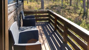 A wooden deck with two wicker chairs and a wooden railing overlooking a forested area. - Sandvikfjellet by Interhome (Eikefjord)