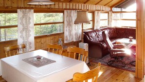A wooden cabin interior with a dining table, chairs, a leather sofa, and a table lamp. - Sandvikfjellet by Interhome (Eikefjord)