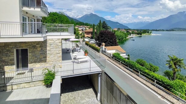 A modern building with a stone facade, a balcony with metal railings, and a view of a lake with mountains in the background. - Orchidea (GLA126) by Interhome (Gera Lario)