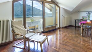 A spacious room with a large sliding glass door leading to a balcony, a wooden chair, a table with a pink tablecloth, and a radiator. - La Becca by Interhome (Domaso)