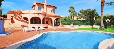 A Mediterranean-style villa with a swimming pool, outdoor seating, and a well-maintained garden.