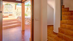 Una escalera conduce a un espacio al aire libre cubierto con paredes de piedra y una reja metálica.