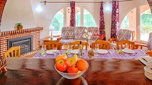 Un comedor con chimenea de ladrillo, mobiliario de madera y una mesa dispuesta para comer.