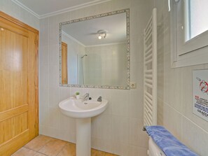 Une salle de bain avec un lavabo blanc, un miroir et un porte-serviettes.