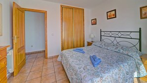 A bedroom with a bed, a wooden wardrobe, a nightstand, and a radiator. - Residencial Puerta de Calpe by Interhome (Calpe/Calp)