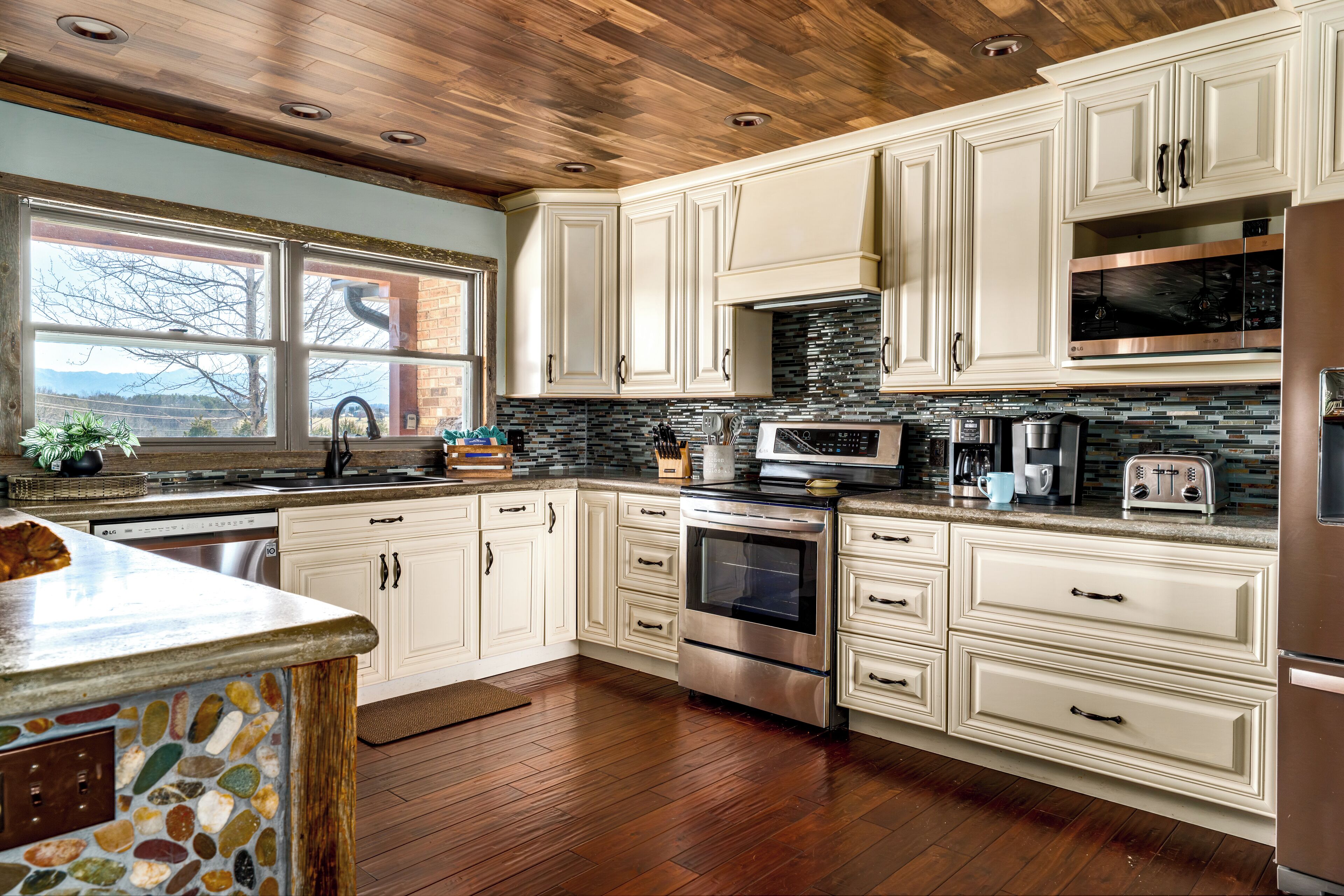 A kitchen with white cabinets, a stone backsplash, and a wooden ceiling.
