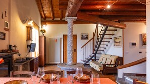 A dining area with a stone column, wooden staircase, and a cozy interior.