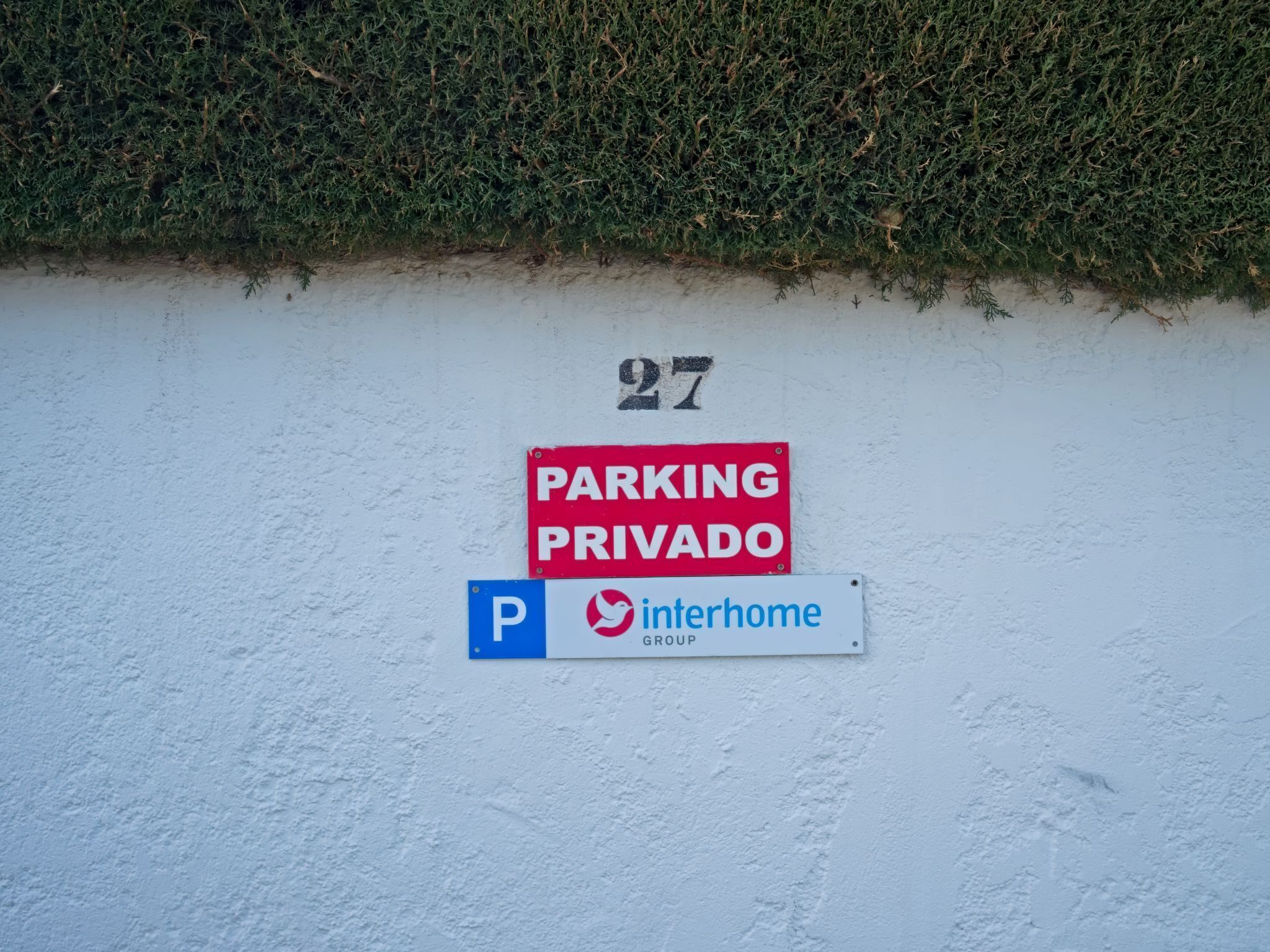 Een muur met een 'PARKING PRIVADO' bord en een 'P interhome GROUP' bord.