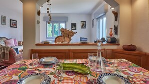 A dining area with a table set for four, a decorative animal head on the counter, and a view of the living room through an archway. - Ruscello by Interhome (San Siro)