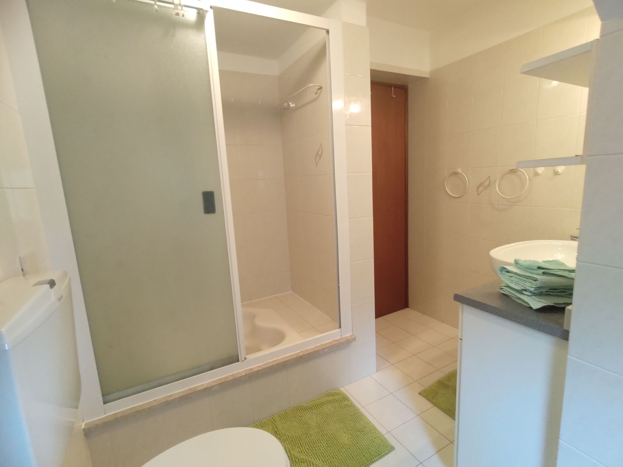 Une salle de bain avec une douche à parois de verre, des toilettes, un lavabo avec un miroir et un porte-serviettes.