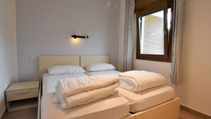 Ein Schlafzimmer mit einem Bett, einem Nachttisch und einem Fenster mit Vorhängen.