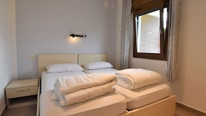 A bedroom with a bed, bedside tables, a wall-mounted light, and a window with curtains. - Villa Vesta by Interhome (Lago d'Idro)