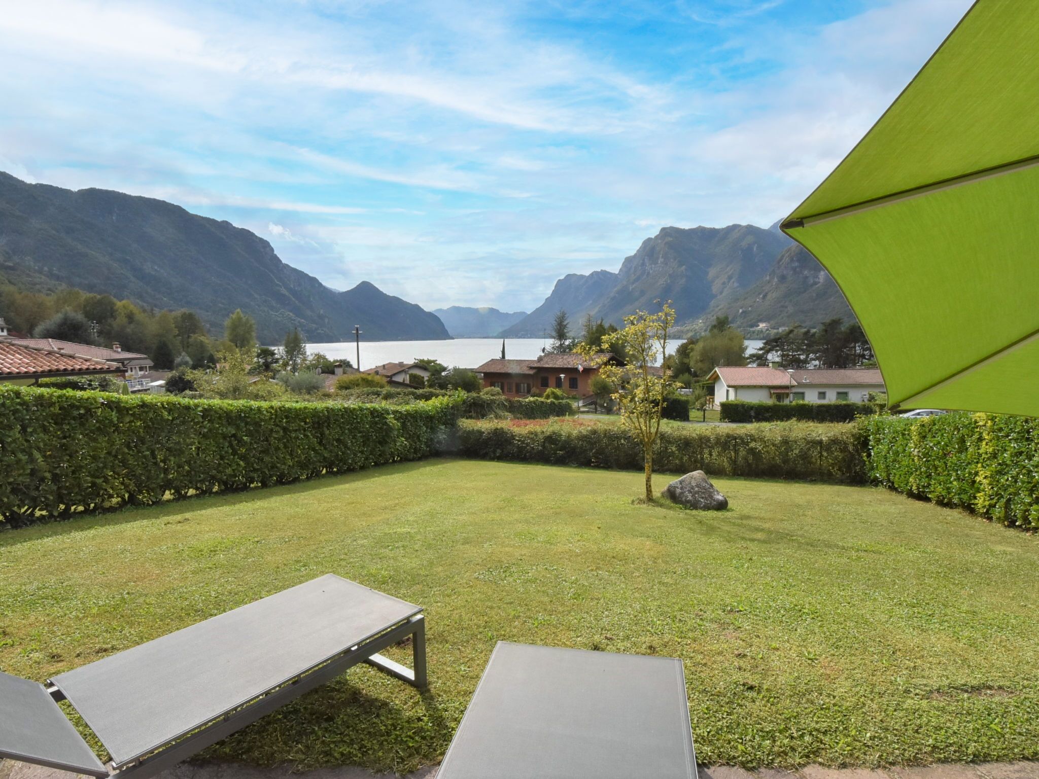 A view of a mountainous landscape with a clear sky, a well-maintained lawn, and two lounge chairs.
