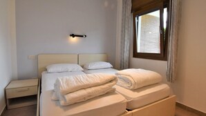 A bedroom with a bed, bedside tables, a wall-mounted light, and a window with curtains. - Villa Vesta by Interhome (Lago d'Idro)
