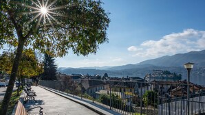 Una cadira al costat d'una passejada marítima, amb vista a edificis i muntanyes a la distància.