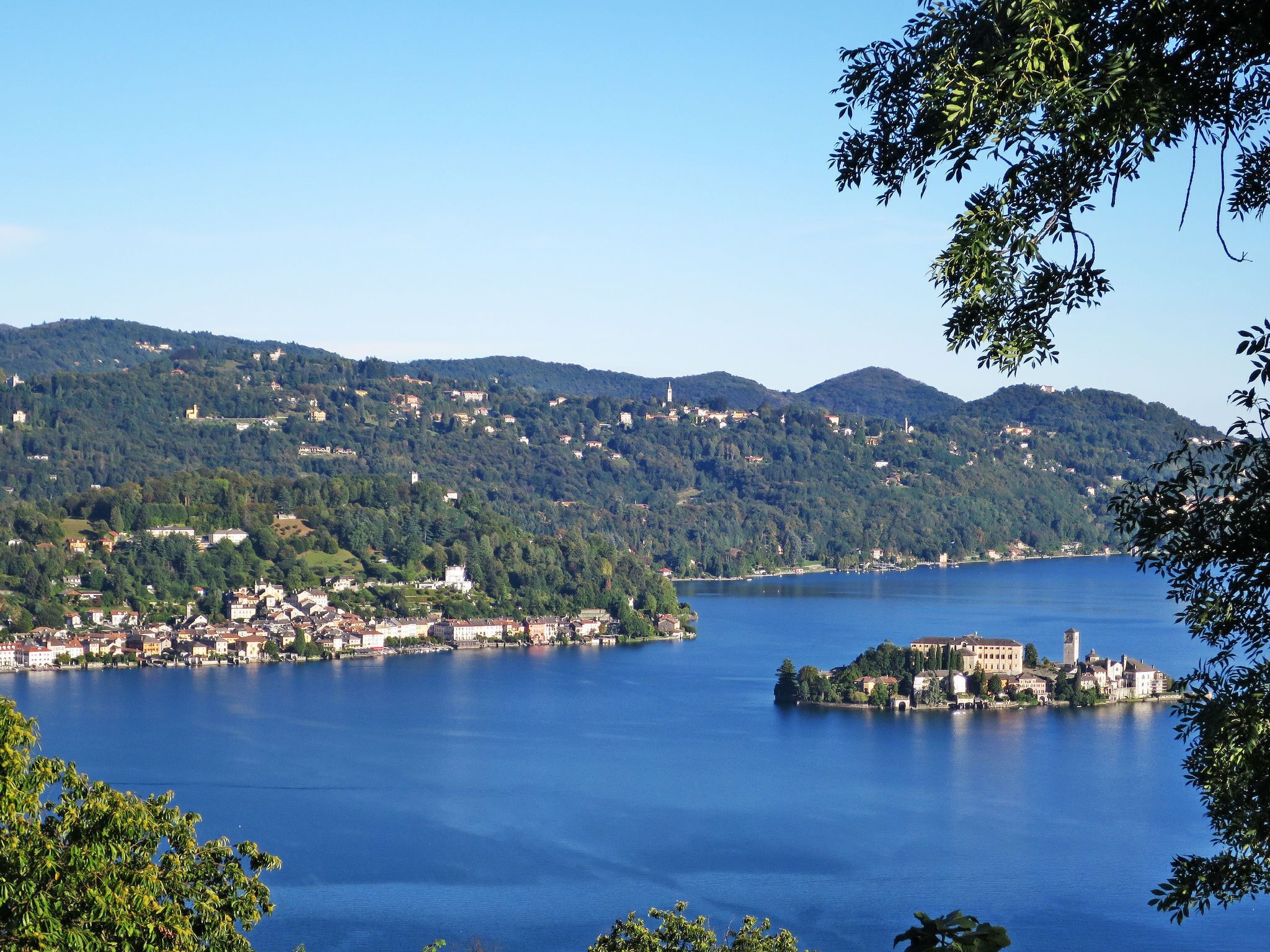 A lakeside town with buildings on the shore and hills in the background.