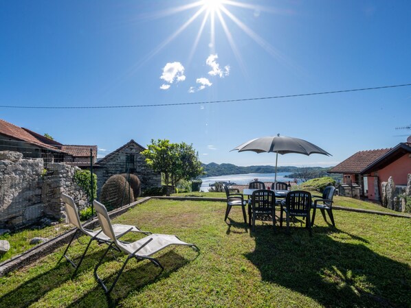 A patio with outdoor furniture, a stone wall, and a view of a lake. - Monte San Giulio by Interhome (Orta San Giulio)