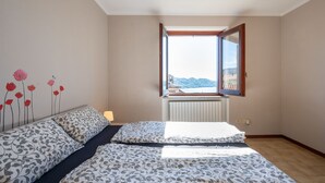 Et soveværelse med en stor seng, et vindue med udsigt til bjergene og en radiator under vinduet.