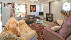 Ein Wohnzimmer mit Sofa, Sesseln, Fernseher, Kamin und Dekorationselementen.