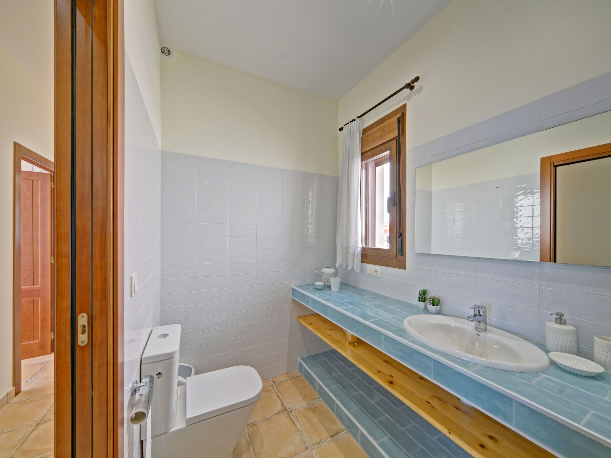 A bathroom with a toilet, sink, and mirror.