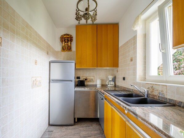 A compact kitchen with a refrigerator, coffee maker, and sink.