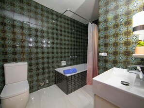 Ein Badezimmer mit gemusterten Fliesen, einer Toilette, einer Badewanne und einem Waschbecken.