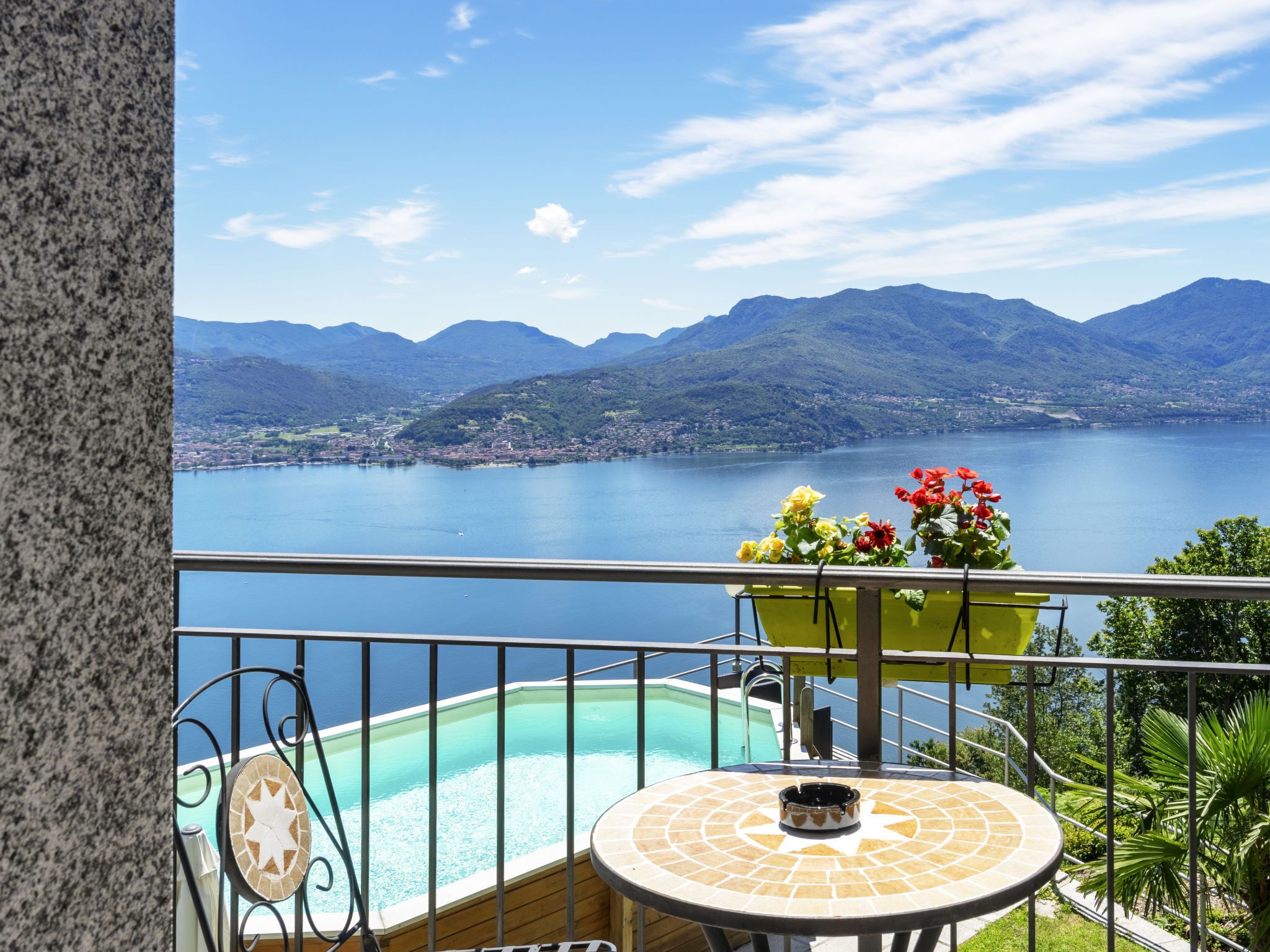 Ein Balkon mit Pool, Tisch und Blick auf See und Berge.