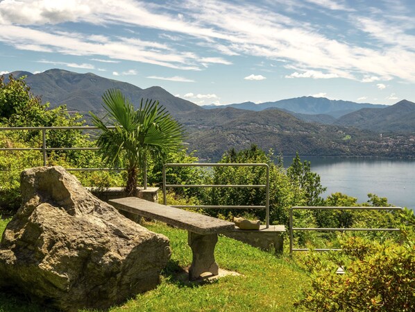 A stone bench overlooking a lake with mountains in the background. - Lo Scoiattolo by Interhome (Cannero Riviera)