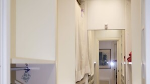 A narrow hallway with a wooden herringbone floor, white walls, and a mirror reflecting the room. - Il Ciliegio by Interhome (Maccagno con Pino e Veddasca)