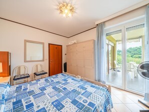 A bedroom with a large bed, a wardrobe, a mirror, and a balcony with outdoor furniture.