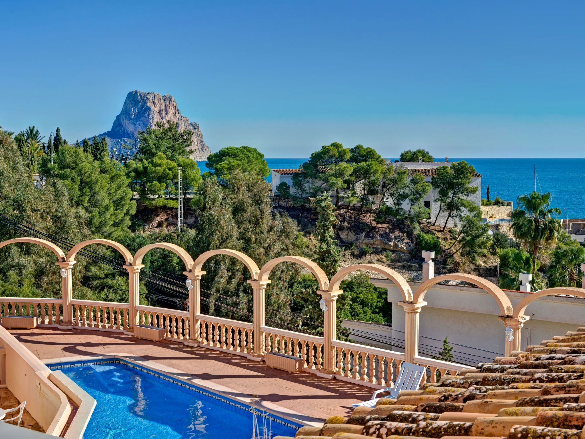 Area piscina con vista sul mare e una montagna sullo sfondo.