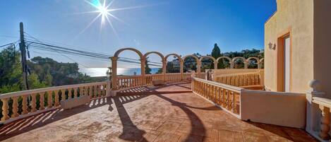 Une terrasse ensoleillée, dotée d’un sol carrelé et d’une balustrade, qui offre une vue imprenable sur un paysage magnifique.