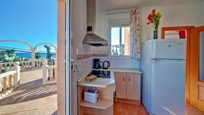 A compact kitchen with a built-in oven, a coffee maker, and a toaster. There is a window with a view of the sea. - Canuta Baja by Interhome (Calpe/Calp)