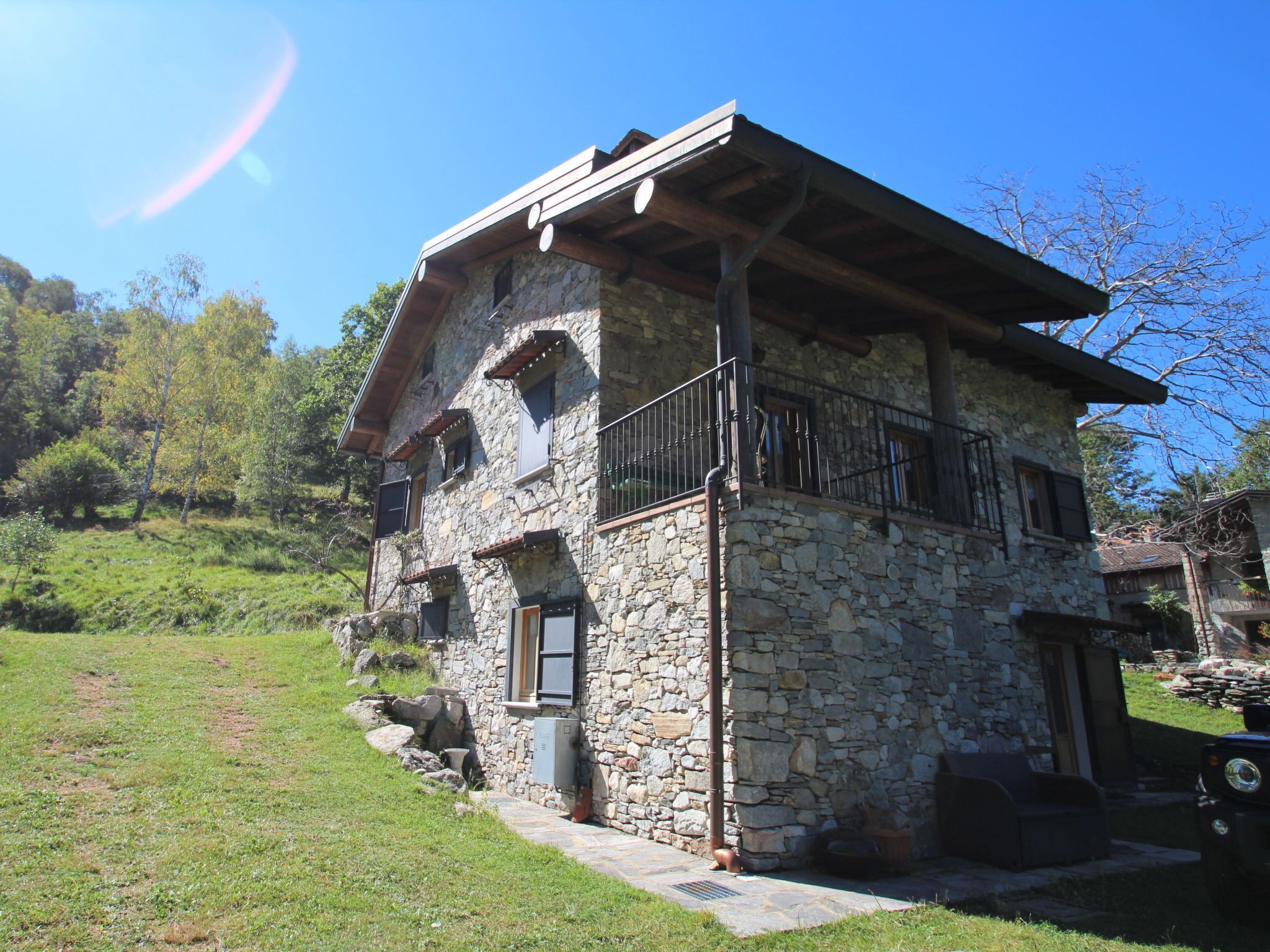 A stone house with a balcony, a wooden door, and a stone wall.