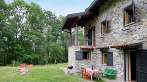 Ein Steinhaus mit Balkon, Grillplatz und Gartenmöbeln.