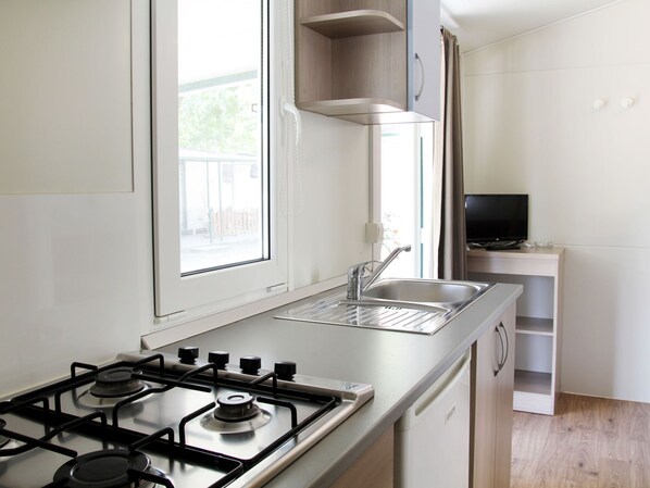 A modern kitchen with a gas stove, a sink, and a window.