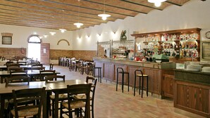 A spacious restaurant with brick walls, wooden tables, and a bar area with various bottles and glasses.
