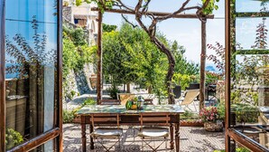Eine Terrasse mit Tisch und Stühlen, umgeben von Pflanzen und einer Pergola.