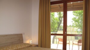 Habitació amb un llit, una tauleta de nit i una finestra amb cortines.