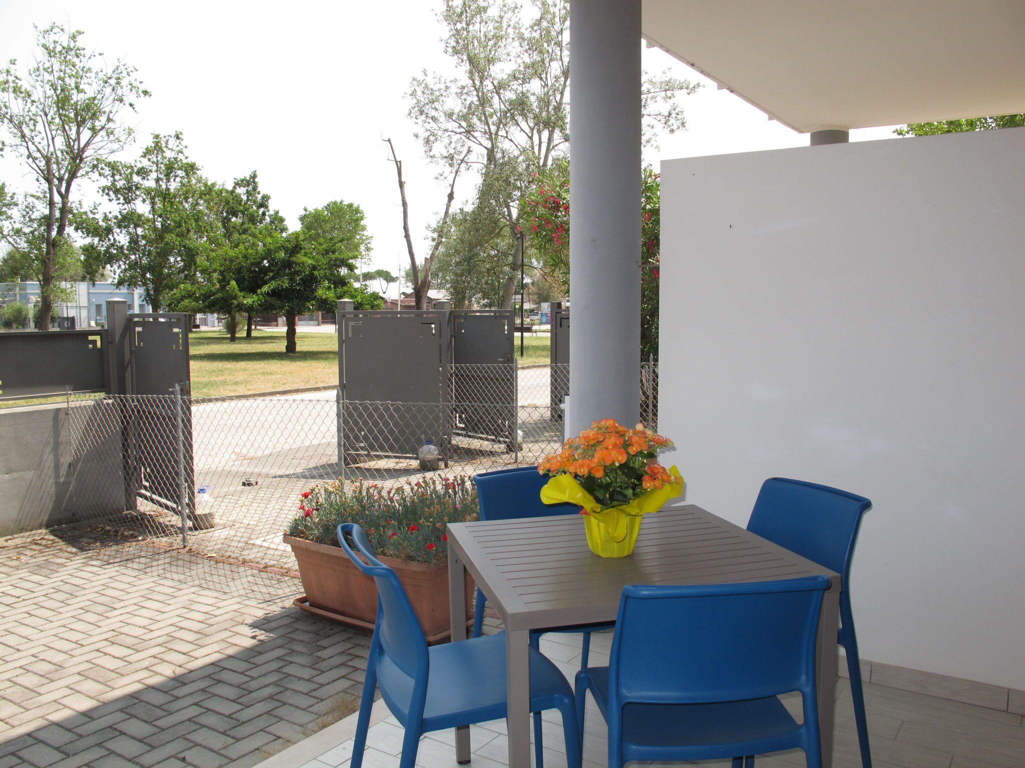 An outdoor patio with a table and chairs, a potted plant, and a yellow bucket.
