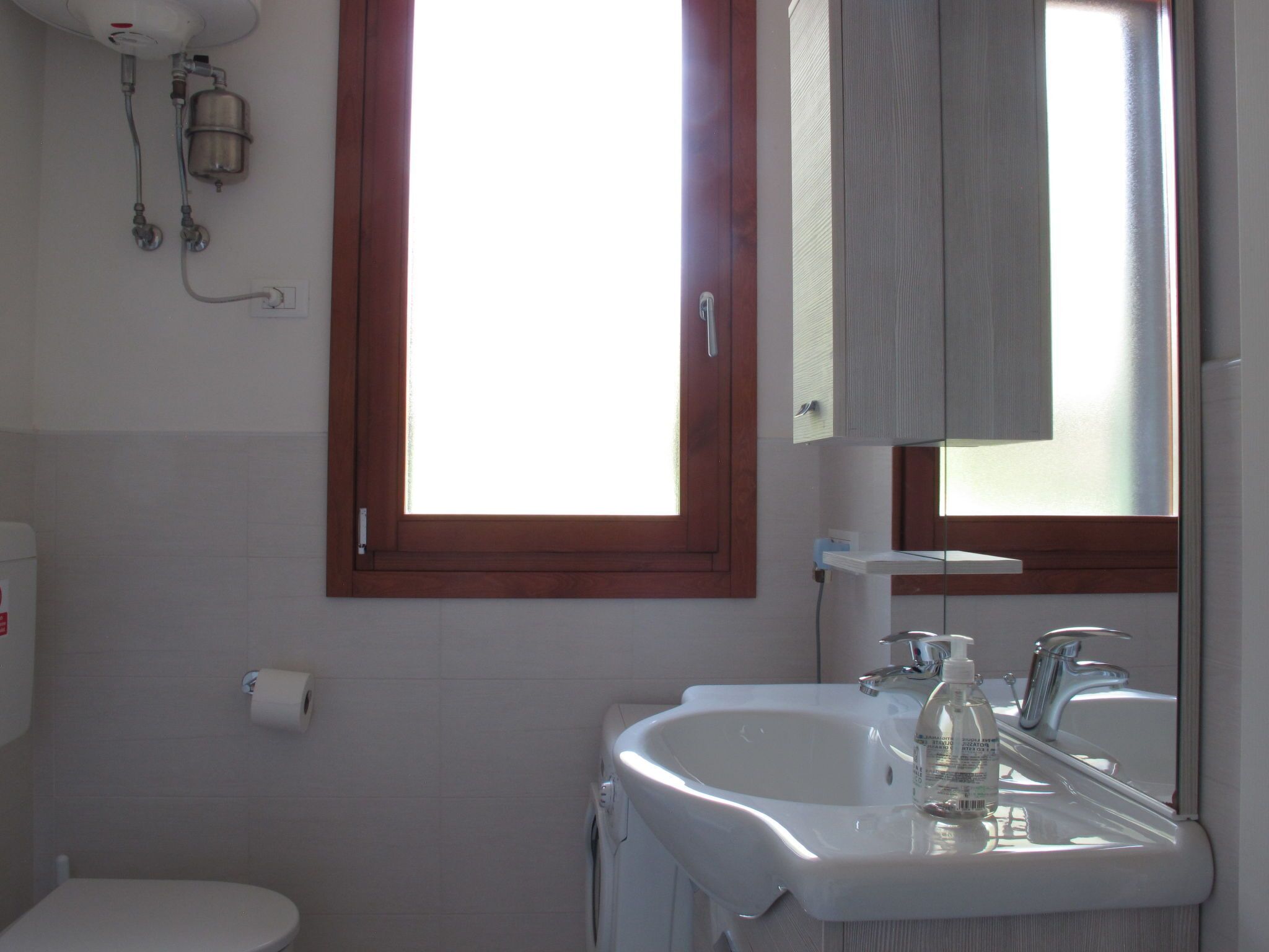 Ein Badezimmer mit Toilette, Waschbecken und Fenster.